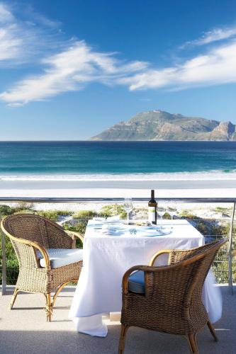 a table with a bottle of wine sits on a balcony with the ocean at Last Word Long Beach in Kommetjie