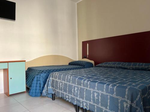 a hotel room with two beds and a television at Fellini Rimini in Rimini