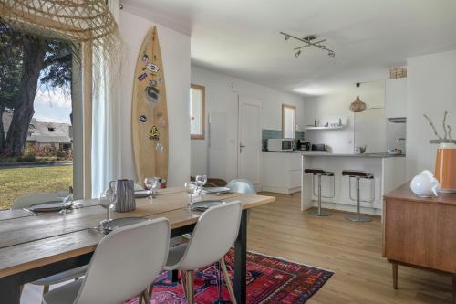 une salle à manger avec une table, des chaises et une planche de surf dans l'établissement Charmante villa tout confort et à 500m de la plage, à Pornichet