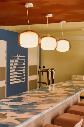 a bar in a restaurant with four lights at Greet Hotel Versailles - Voisins Le Bretonneux in Voisins-le-Bretonneux
