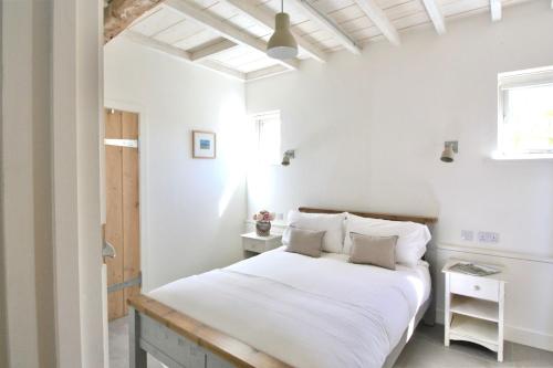 a bedroom with white walls and a bed with white sheets at Gull Farm Barn in Burgh