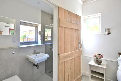 Łazienka z umywalką i drewnianymi drzwiami w obiekcie Gull Farm Barn w mieście Burgh