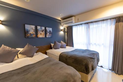 a hotel room with two beds and a window at Ocean Niponichi in Osaka