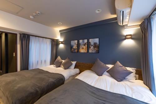 two beds in a room with blue walls and windows at Ocean Niponichi in Osaka