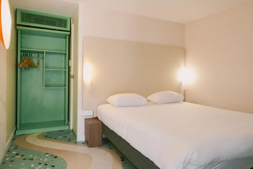a bedroom with a white bed and a green door at Greet Hotel Versailles - Voisins Le Bretonneux in Voisins-le-Bretonneux