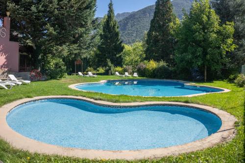 uma piscina num quintal com árvores e montanhas em Hotel Cardós em Ribera de Cardós