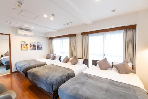 three beds in a hotel room with windows at Ocean Niponichi in Osaka