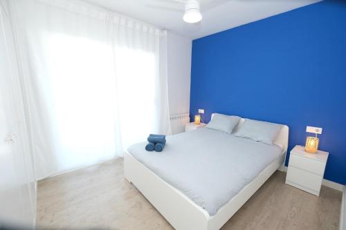 - une chambre avec un lit blanc et un mur bleu dans l'établissement La Brisa Marina, à Roda de Bará