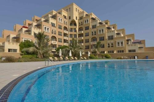 a large apartment building with a large swimming pool at Luxurious Private Beach & Pool, fully Furnished 1BR Apartment at Marjan Island Ras al khaimah in Ras al Khaimah