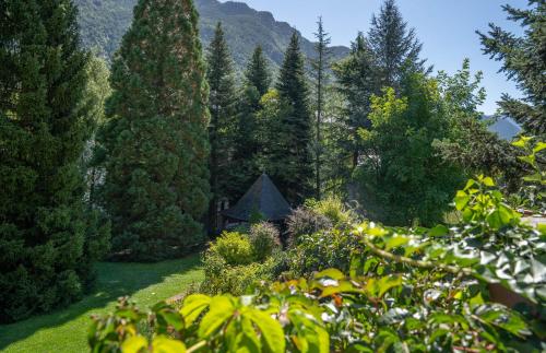 a garden with trees and a house in the background at Hotel Cardós in Ribera de Cardós