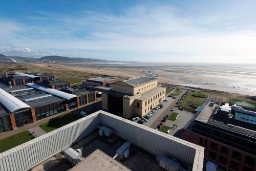 an aerial view of a building next to the beach at UPP Bay Campus Swansea in Swansea