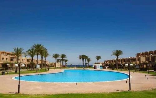 ein großer Pool mit Palmen und Gebäuden in der Unterkunft Chalet first floor two bedrooms In Stella De Mare Ain El Sokhna For Families only in Ain Suchna