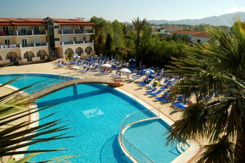 a large swimming pool with blue chairs and a hotel at Majestic Hotel & Spa in Laganas