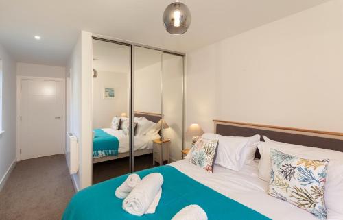 1 dormitorio con cama y espejo en 1 Challacombe - Luxury Apartment at Byron Woolacombe, only 4 minute walk to Woolacombe Beach!, en Woolacombe