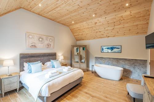 a bedroom with a large bed and a bath tub at Osprey Lodge 1 with Hot Tub in Newton Stewart