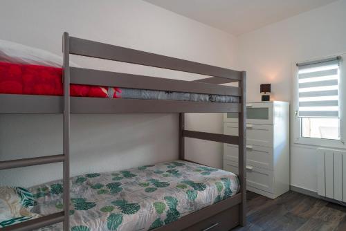 1 Schlafzimmer mit 2 Etagenbetten und einem Fenster in der Unterkunft Ti Kréol - 5 minutes des plages in Saint-Nic