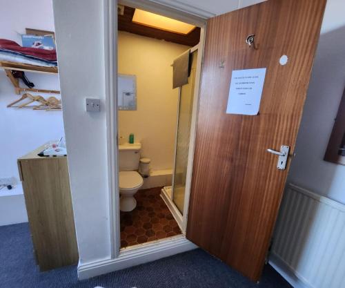 a bathroom with a toilet and a wooden door at The Moorfield in Blackpool