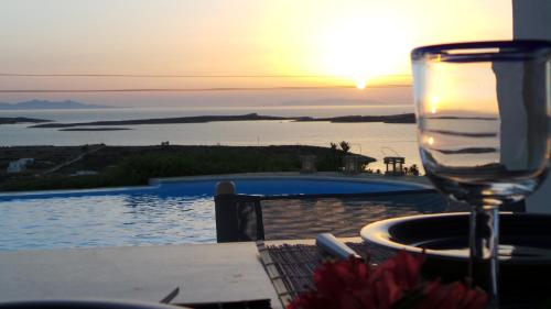 een glas wijn op een tafel naast een zwembad bij VILLA MIA PAROS in Agia Irini Paros