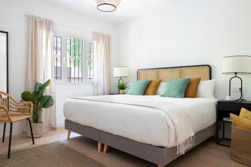 a white bedroom with a large bed with blue pillows at Magno Apartments Castelar in Seville