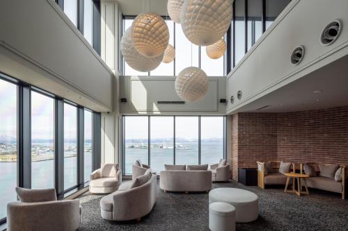 a lobby with chairs and tables and large windows at Tokyu Stay Hakodate Asaichi Akarinoyu in Hakodate