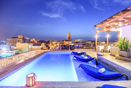 uma piscina no telhado de um edifício com espreguiçadeiras azuis em NH Royal Urban Cartagena em Cartagena das Índias