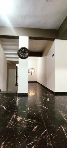 a room with a black marble floor and a clock at BILVA COMFORTS in Madhugiri