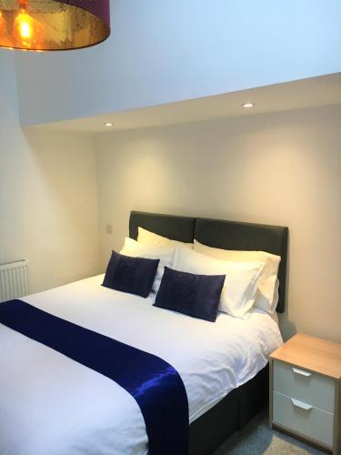 a bedroom with a large bed with blue and white pillows at Jopes Mill and Lodge in Looe