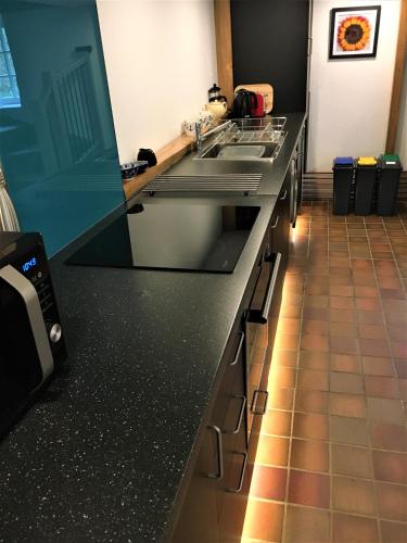 a kitchen with a black counter top with a sink at Jopes Mill and Lodge in Looe