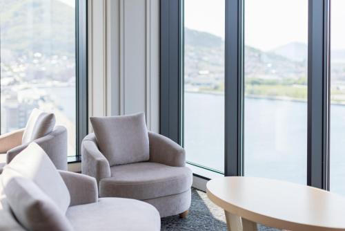 a room with chairs and a table and windows at Tokyu Stay Hakodate Asaichi Akarinoyu in Hakodate