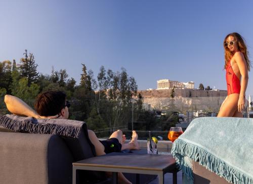 a man and a woman are sitting on a couch at Neoma in Athens