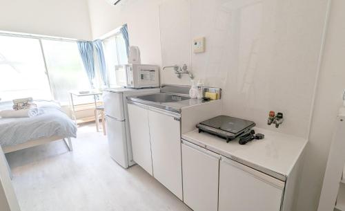 a small white kitchen with a sink and a bed at 101 Hideaway, Apartment with loft in Tokyo