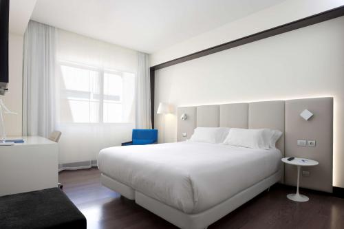 a bedroom with a large white bed and a window at NH Madrid Lagasca in Madrid
