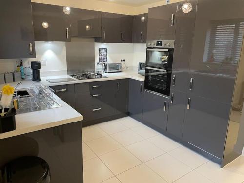 a kitchen with black cabinets and white tile floors at Fresh & Spacious New Build Home in Church Coppenhall