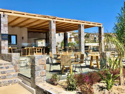 un patio con mesas y sillas bajo un pabellón en Helios Beach Hotel & Bungalows, en Karpathos