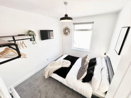 韋茅斯的住宿－Stylish & Spacious 4 Bed Coastal Haven in Weymouth，卧室拥有白色的墙壁,配有带枕头的床铺。