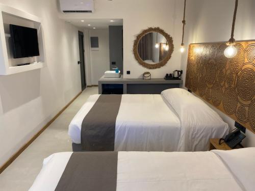 a hotel room with two beds and a mirror at Helios Beach Hotel & Bungalows in Karpathos