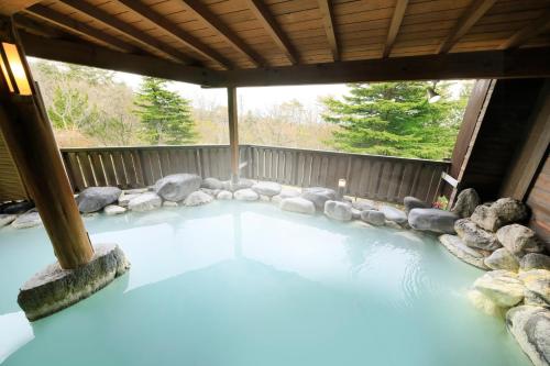 una piscina de agua en un patio con rocas en FOURTREAT plus NASUKOGEN, en Nasu