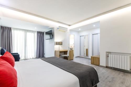 a bedroom with a large white bed and a desk at Sweet Hotel Renasa in Valencia