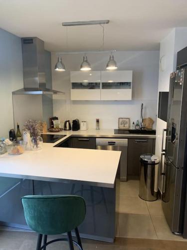 une cuisine avec un comptoir blanc et un fauteuil vert dans l'établissement Bel appartement, grande terrasse, à Boulogne-Billancourt