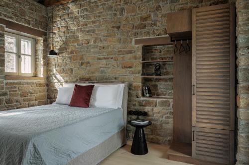 a bedroom with a bed and a brick wall at LozArt Traditional Stone House in Ellinikón