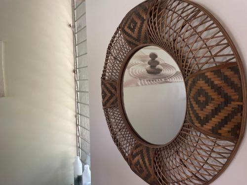 a rattan mirror with a rattan frame on a wall at Nolan garden house in whitfield in Stratford