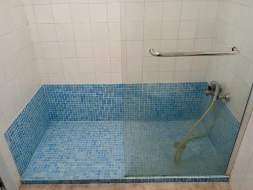La salle de bains est pourvue d'une douche et d'une baignoire carrelée de bleu. dans l'établissement Alcôa House, à Alcobaça