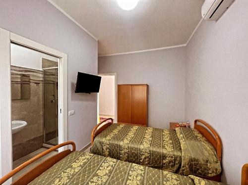 two beds in a small room with a bathroom at Sweet Stay in Fiumicino