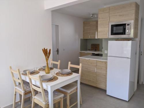 Il comprend une cuisine équipée d'une table avec des chaises et d'un réfrigérateur blanc. dans l'établissement Appartement T4 proche plage et vieille ville, à Antibes