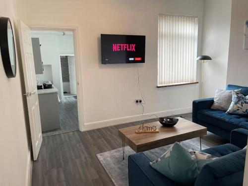 sala de estar con sofá azul y TV en Cosy & Fresh Home en Stoke on Trent