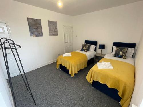 two beds in a room with yellow sheets at Cosy & Fresh Home in Stoke on Trent