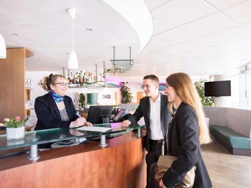 a group of people standing at a reception desk at Novotel Suites Hannover in Hannover