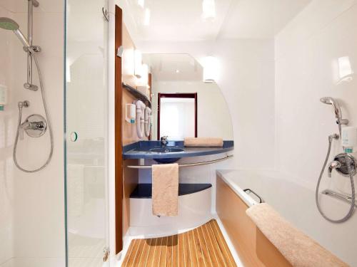 La salle de bains est pourvue d'un lavabo et d'une douche. dans l'établissement Novotel Suites Hannover, à Hanovre