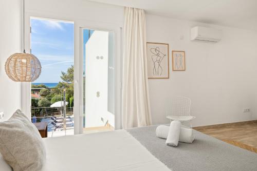 Dormitorio blanco con cama y ventana grande en Villa Sunset, en Son Bou