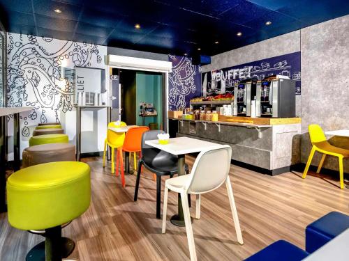 een restaurant met kleurrijke stoelen en een tafel en een bar bij ibis budget Menton Bord de Mer in Menton